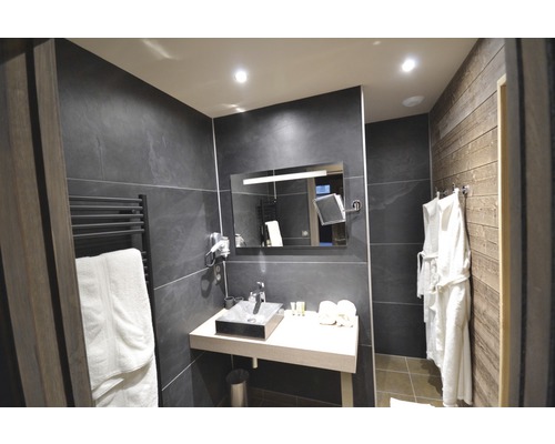 Badezimmer mit Waschbecken, Spiegel, Handtuchwärmer und Bademänteln.