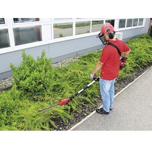Mann schneidet Hecke mit einer Akku-Heckenschere mit Teleskopstiel und Schutzausrüstung