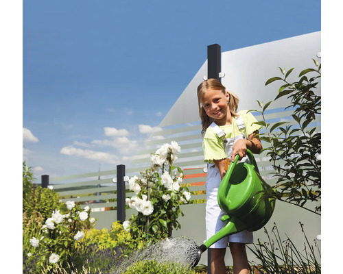 Mädchen giesst Gartenpflanzen mit einer Giesskanne