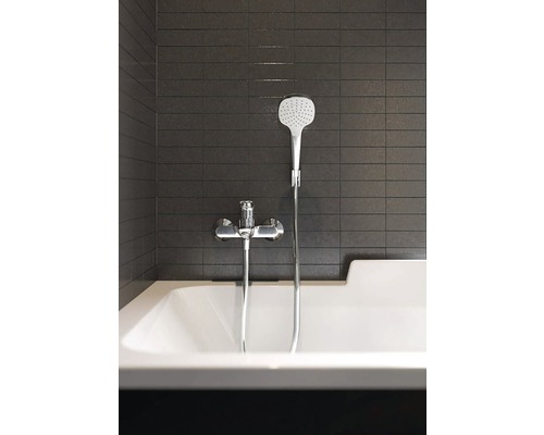 Badezimmer mit Badewanne, Armatur und Handbrause vor dunklen Fliesen