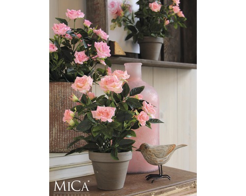 Dekorative Rosen im Topf auf einem Tisch mit einer Holzdekoration in Vogelform und einer Vase.