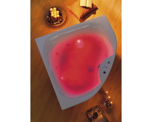 Eckbadewanne mit rotem Licht, Kerzen und Buch auf dem Boden für entspannende Atmosphäre