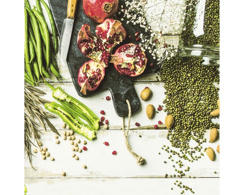 Arrangement mit Granatapfel, grünen Bohnen, grünen Mungbohnen, Mandeln und Gewürzen auf einem Schneidebrett