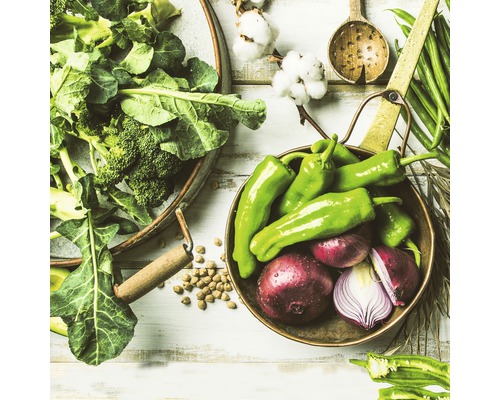 Nature morte avec des légumes frais, notamment du brocoli, des poivrons et des oignons, disposés dans des bols et sur une surface en bois.