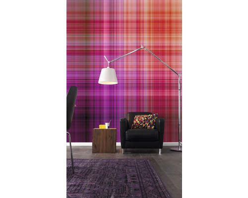 Un salon avec un papier peint à motifs, un fauteuil, un lampadaire et un tapis.