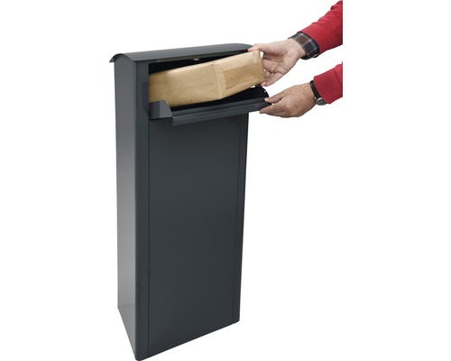 Person legt eine Sendung in einen Paketbriefkasten.