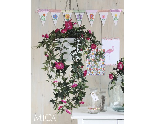 Dekorative Szene mit hängender Kunstpflanze in einem Topf und Dekorationsgegenständen auf einem Tisch.