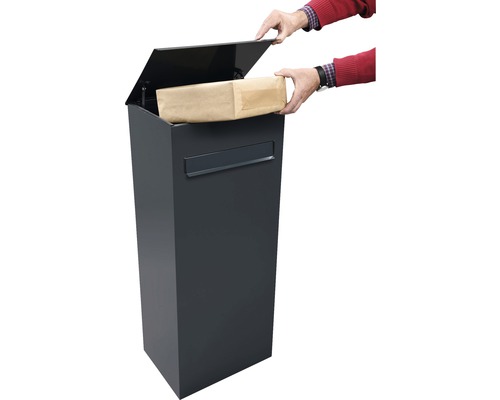 Person legt ein Paket in einen anthrazitfarbenen Paketbriefkasten