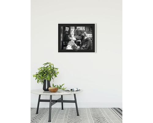 Photo en noir et blanc encadrée d''un couple qui s''embrasse, accrochée au-dessus d''une table d''appoint avec un vase de fleurs