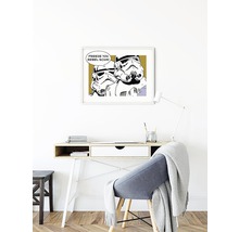 Un bureau avec un bureau, une chaise et une impression Star Wars encadrée au mur.