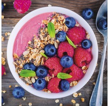 Bol avec smoothie, myrtilles, framboises et muesli sur une table en bois