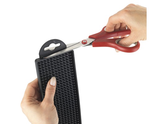 Eine Person schneidet mit einer Schere ein Schneidepad aus Gummi.