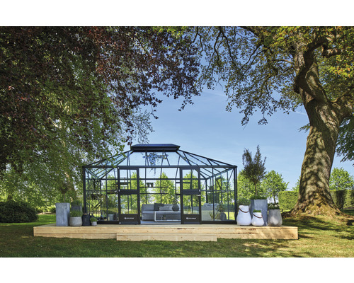 Serre avec cadre en acier et verre sur terrasse en bois dans un jardin