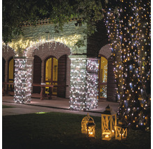 Bâtiment éclairé avec des guirlandes lumineuses et des lanternes dans le jardin