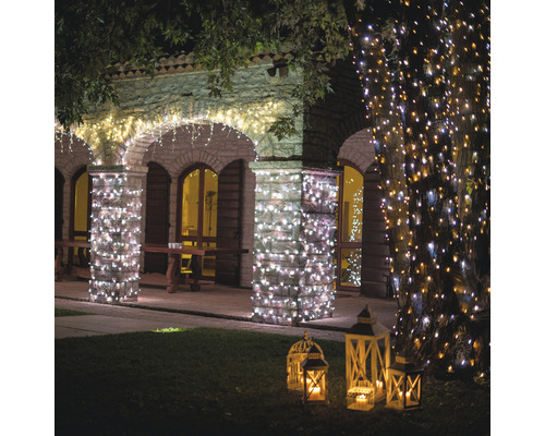 Bâtiment éclairé avec des guirlandes lumineuses et des lanternes dans le jardin