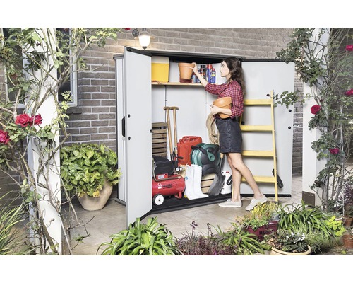 Gartenszene mit einer Frau, die Gartengeräte in einem Geräteschuppen verstaut