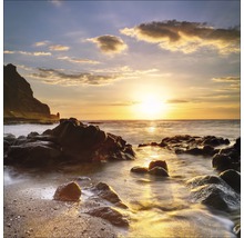 Un paysage côtier avec des rochers dans l''eau au coucher du soleil.