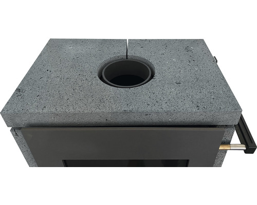 Detailansicht eines Kaminofens mit Steinverkleidung und Rauchrohranschluss