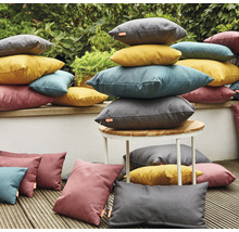 Scène avec des coussins d''extérieur empilés de différentes formes et couleurs sur une terrasse