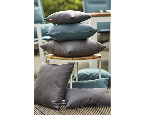 Coussins gris et bleus variés sur une table et un plancher en bois