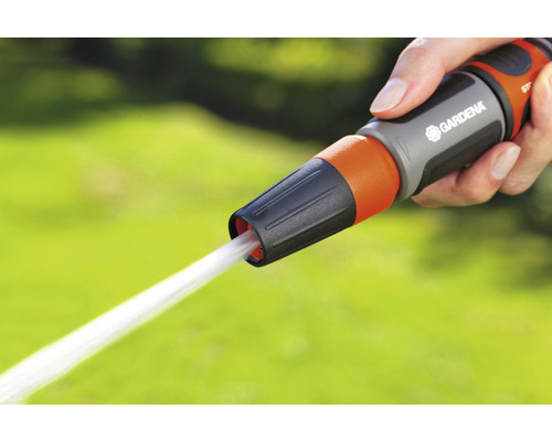 Une main tient un pistolet d''arrosage de la marque Gardena d''où sort un jet d''eau.
