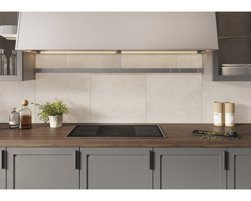 Küchenszene mit Induktionskochfeld, Dunstabzugshaube und Küchenutensilien auf einer Arbeitsplatte