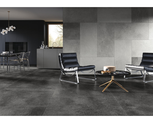 Salon moderne avec carrelage de sol gris, carrelage mural aspect pierre et fauteuils en cuir noir.