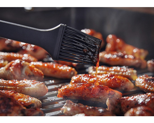 Pinceau à gril badigeonnant des aliments sur un gril