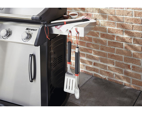 Barbecue à gaz avec ustensiles et torchon sur un mur en briques