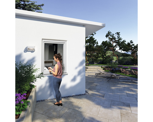 Scène d''une maison de jardin moderne avec une femme à la fenêtre et un espace extérieur pavé.