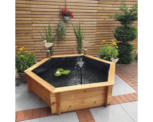 Bassin hexagonal avec cadre en bois, film pour bassin, nénuphar et fontaine dans le jardin.