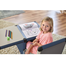Fille assise à une table d''enfant avec des crayons et un livre de coloriage