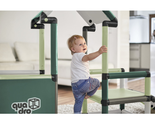Kleines Kind klettert auf ein QUADRO Klettergerüst im Innenbereich.