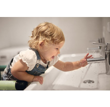 Enfant jouant avec un robinet dans un lavabo de salle de bain