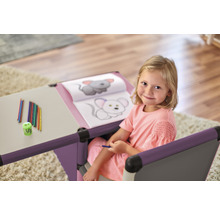 Fille à un bureau d''enfant avec livre de coloriage, crayons et taille-crayon