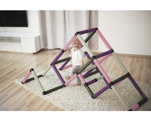 Kleines Kind spielt auf einer Indoor Kletterstruktur im Wohnzimmer.