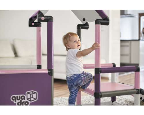 Kleines Kind klettert auf ein Quadro Klettergerüst im Innenbereich