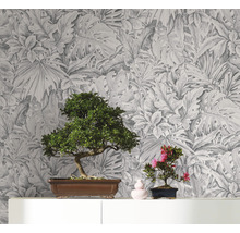 Dekorative Tapete mit botanischem Blätterdesign als Hintergrund für zwei Bonsai Pflanzen auf einem Regal