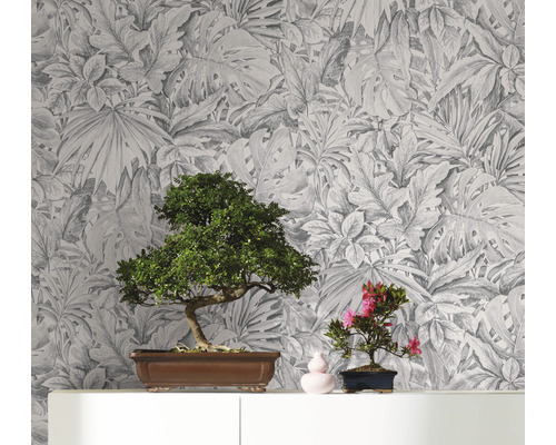 Dekorative Tapete mit botanischem Blätterdesign als Hintergrund für zwei Bonsai Pflanzen auf einem Regal