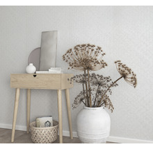 Dekorative Szene mit Holztisch, weißer Vase mit Blumen und geometrischer Tapete