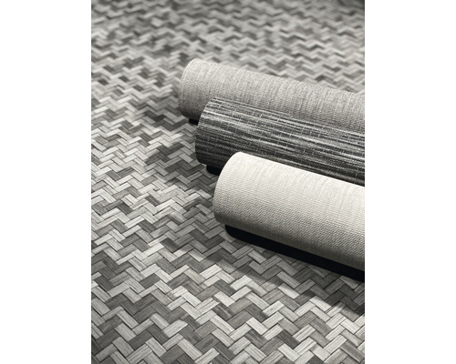 Drei Rollen Teppich auf einem geflochtenen Untergrund.