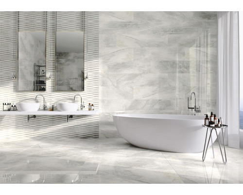 Salle de bain lumineuse avec baignoire, double vasque et carrelage mural et au sol imitation marbre.