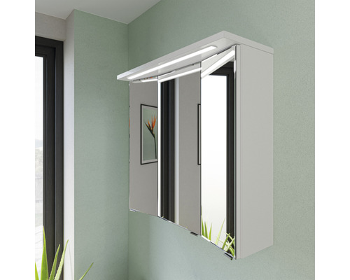 Spiegelschrank mit Beleuchtung und drei Spiegeltüren an einer Wand montiert