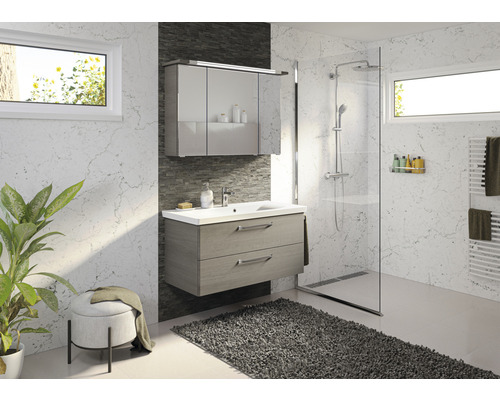 Helles Badezimmer mit Waschtisch, Spiegelschrank, Dusche und Heizkörper.