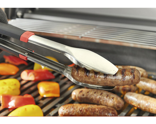 Pince à grill tient une saucisse au-dessus d''une grille