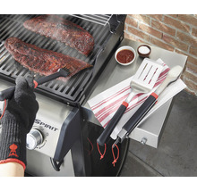 Préparation de nourriture sur un gril avec des ustensiles de gril et des gants résistants à la chaleur.