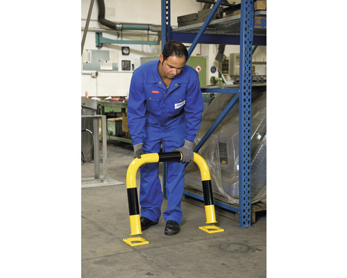 Un homme monte une protection anti-collision jaune et noire devant une étagère