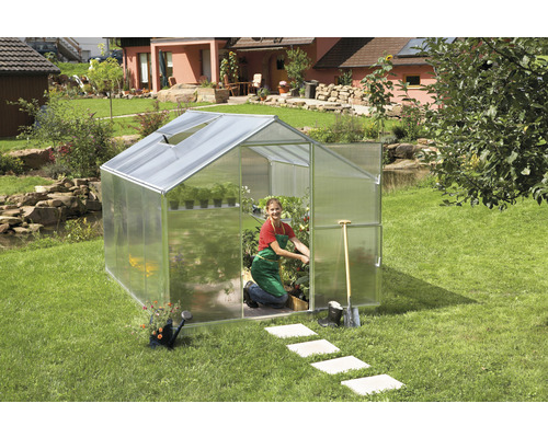 Gewächshaus gutta F4 Polycarbonat 6 mm 227 x 300 cm silber Gewächshaus im Garten mit Gärtnerin und Gartengeräten