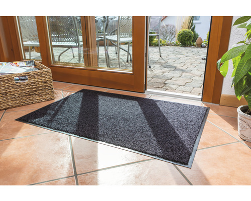 Graue Fußmatte vor einer Terrassentür auf Fliesenboden