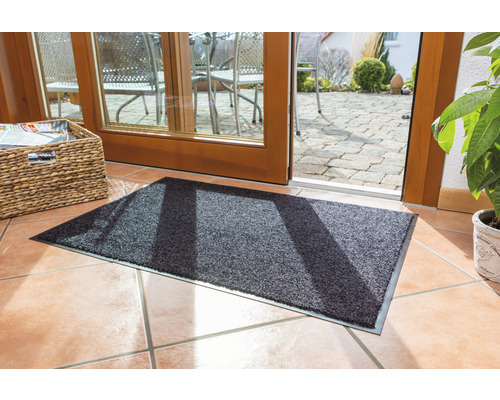 Tapis de sol gris devant une porte de terrasse sur un sol carrelé.